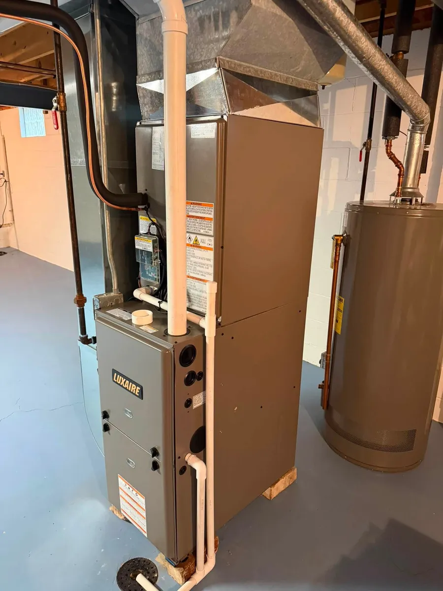 A new high-efficiency furnace AK installed in a basement, vented with white plastic pipe